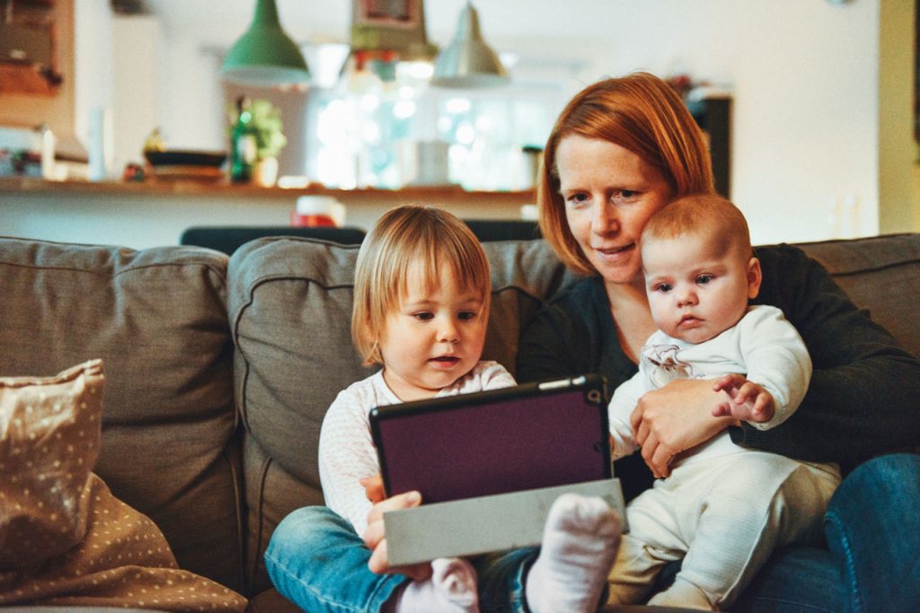 Two young children and their mother are using a tablet.