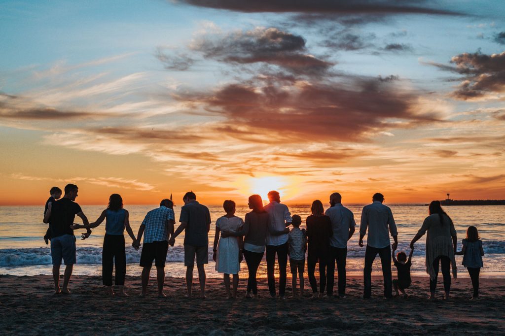 A group of families experiencing a beautiful sunset at the beach.